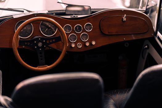 Close-up of a vintage car interior featuring a wooden dashboard and classic steering wheel.