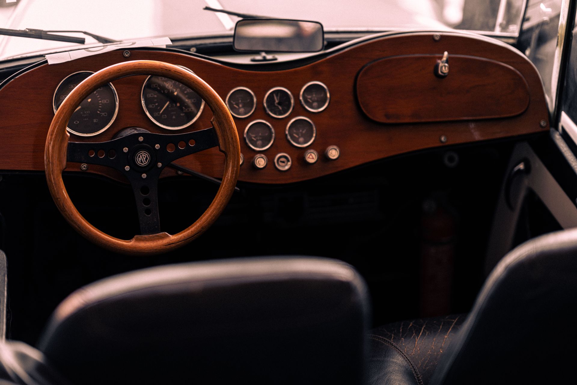 Close-up of a vintage car interior featuring a wooden dashboard and classic steering wheel.