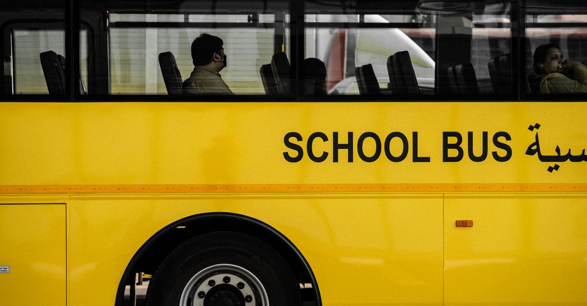 A modern yellow school bus with passengers seen through the windows. Ideal for urban transportation