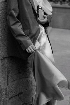 Black and white photo of a woman in a blazer and satin dress on the city streets.