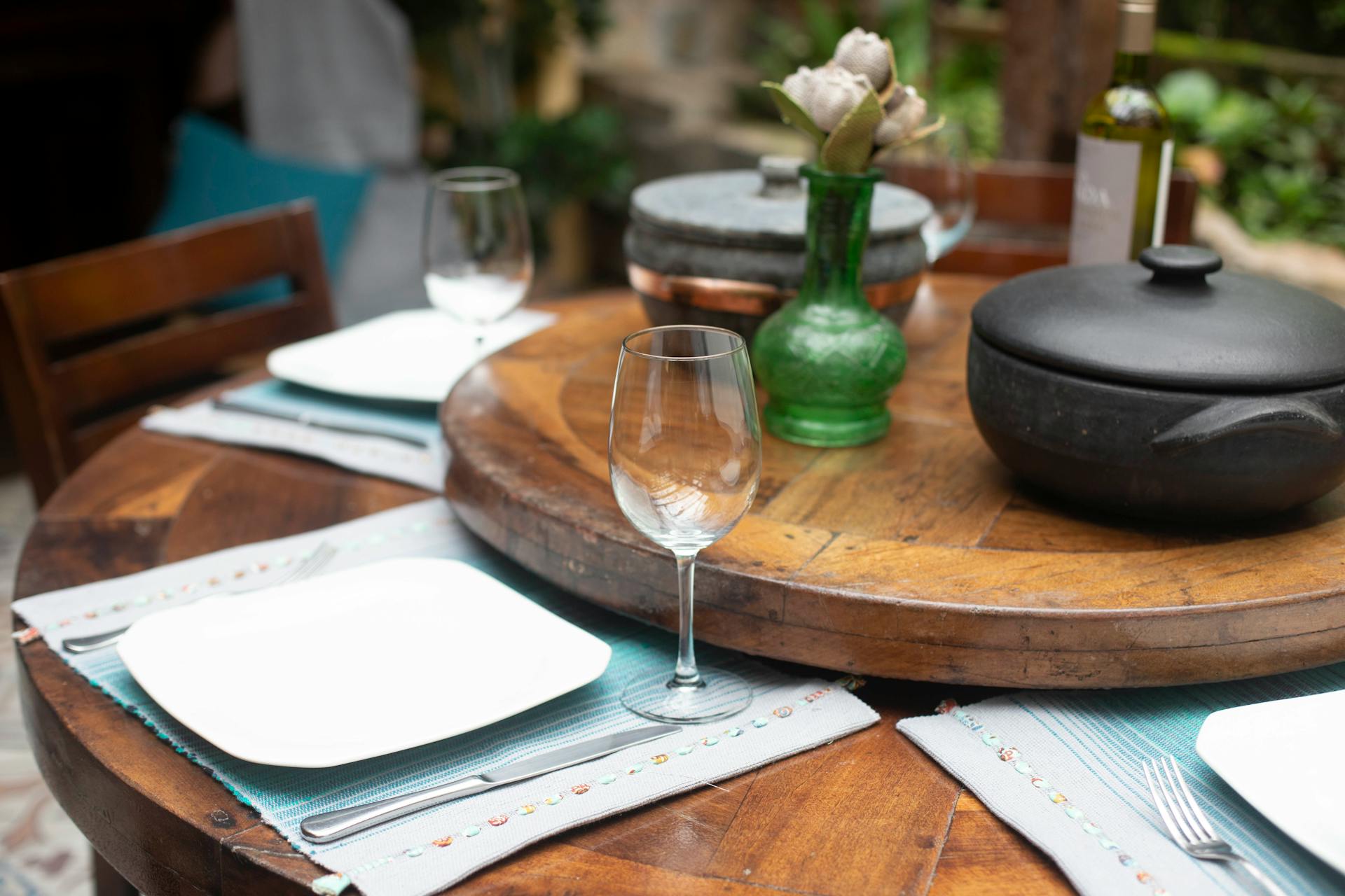 A beautifully set wooden dining table with wine, glassware, and tableware in an elegant setting.