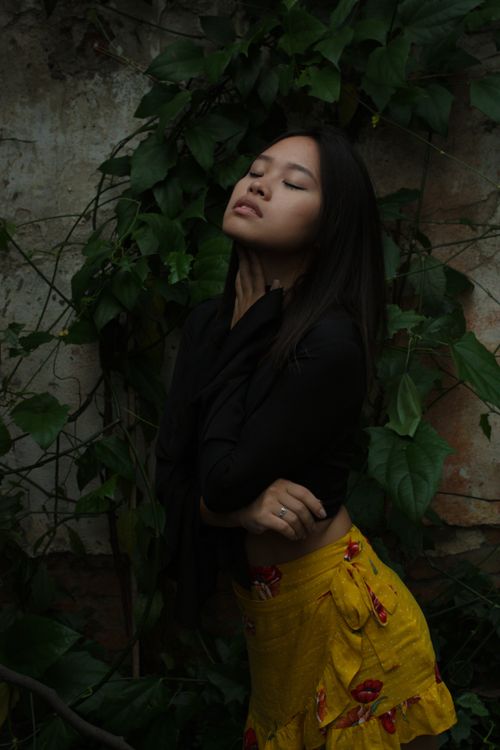 Free A stylish young woman poses gracefully among vibrant leaves, embracing nature's beauty outdoors. Stock Photo
