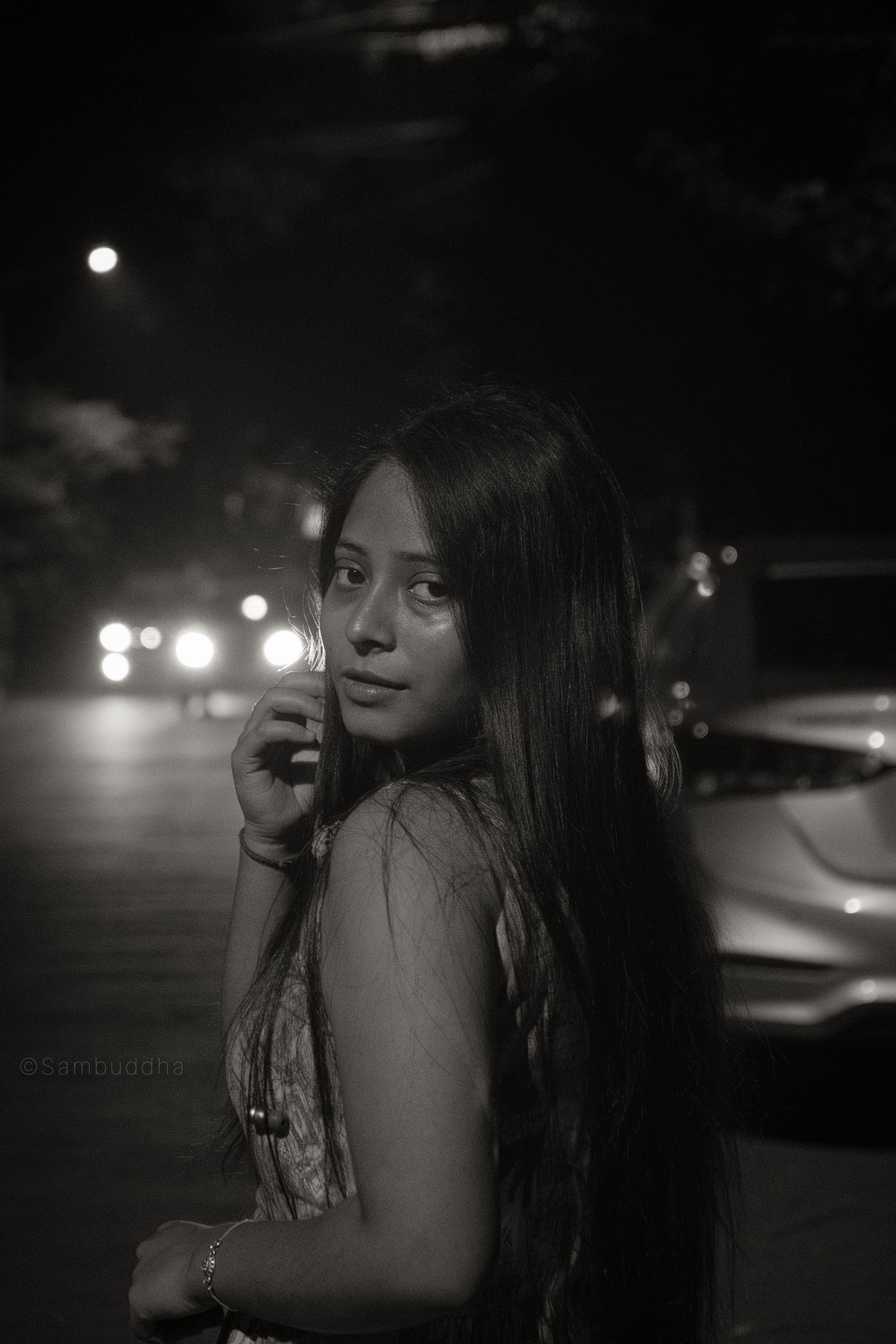 A captivating black and white portrait of a young woman at night, exhibiting mystery and elegance.