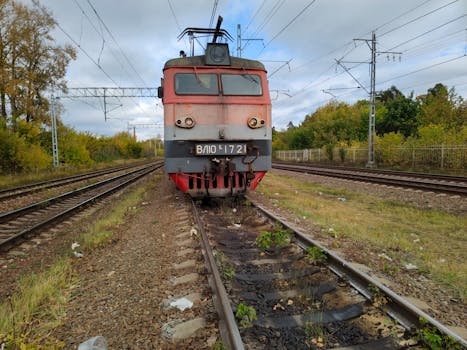 Vintage electric locomotive on railway track in autumn setting.