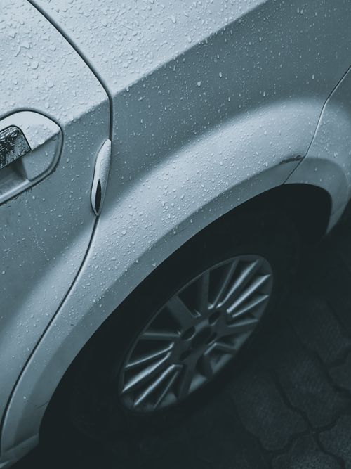 Free Detailed shot of a car's wheel arch with rain droplets, showcasing texture and design. Stock Photo