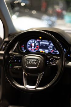 Close-up of a modern car interior focusing on the steering wheel and dashboard controls.