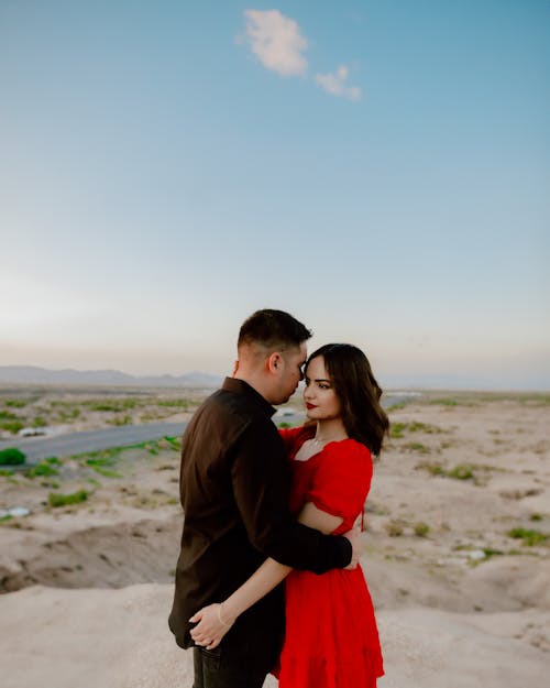 Woman in Red Dress Embracing Man in Black Shirt