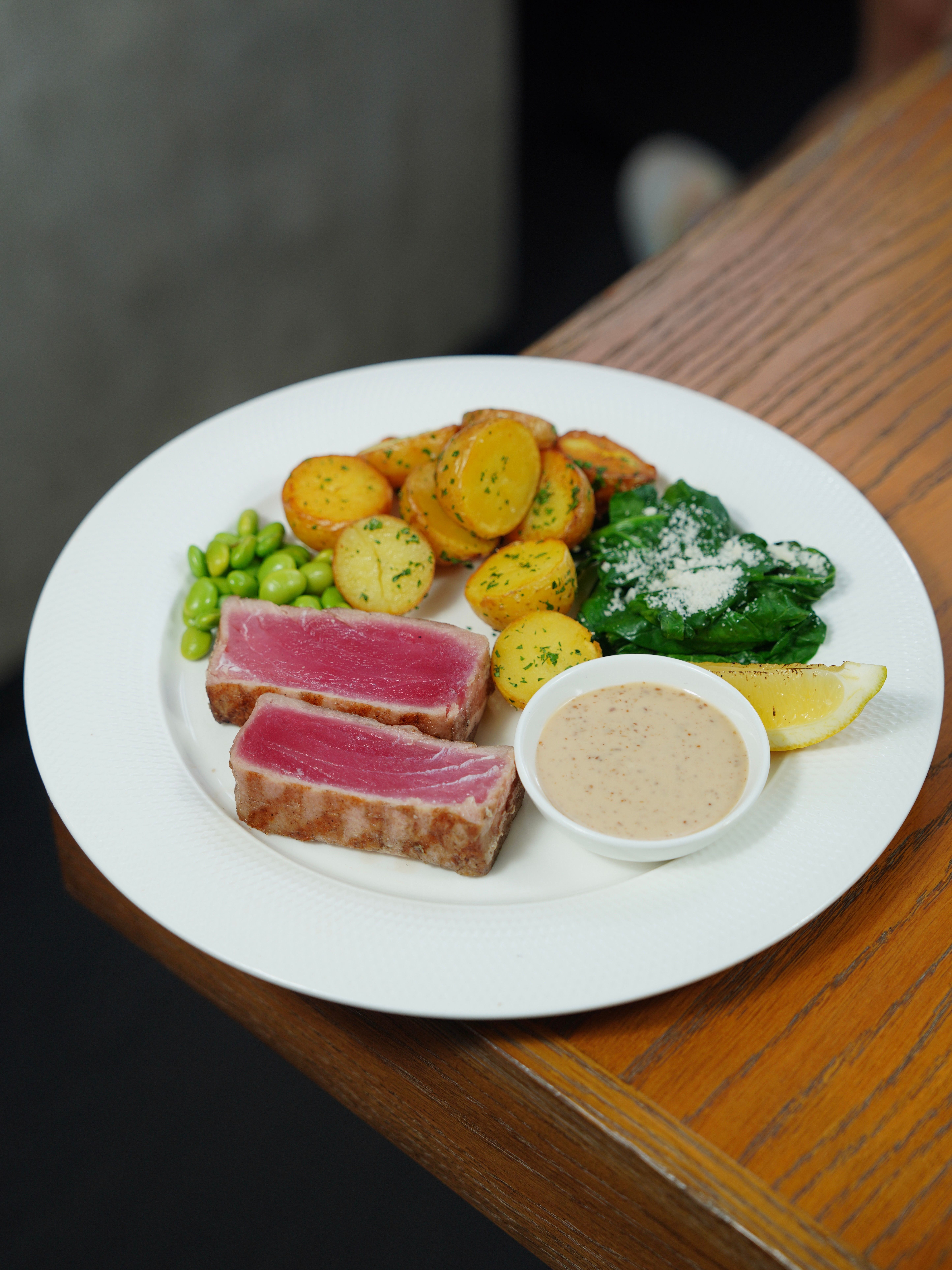 Thinly sliced eye of round steak fanned out on a wooden board, showing a deep brown crust and pink medium-rare center, with a pat of herb butter melting on top.