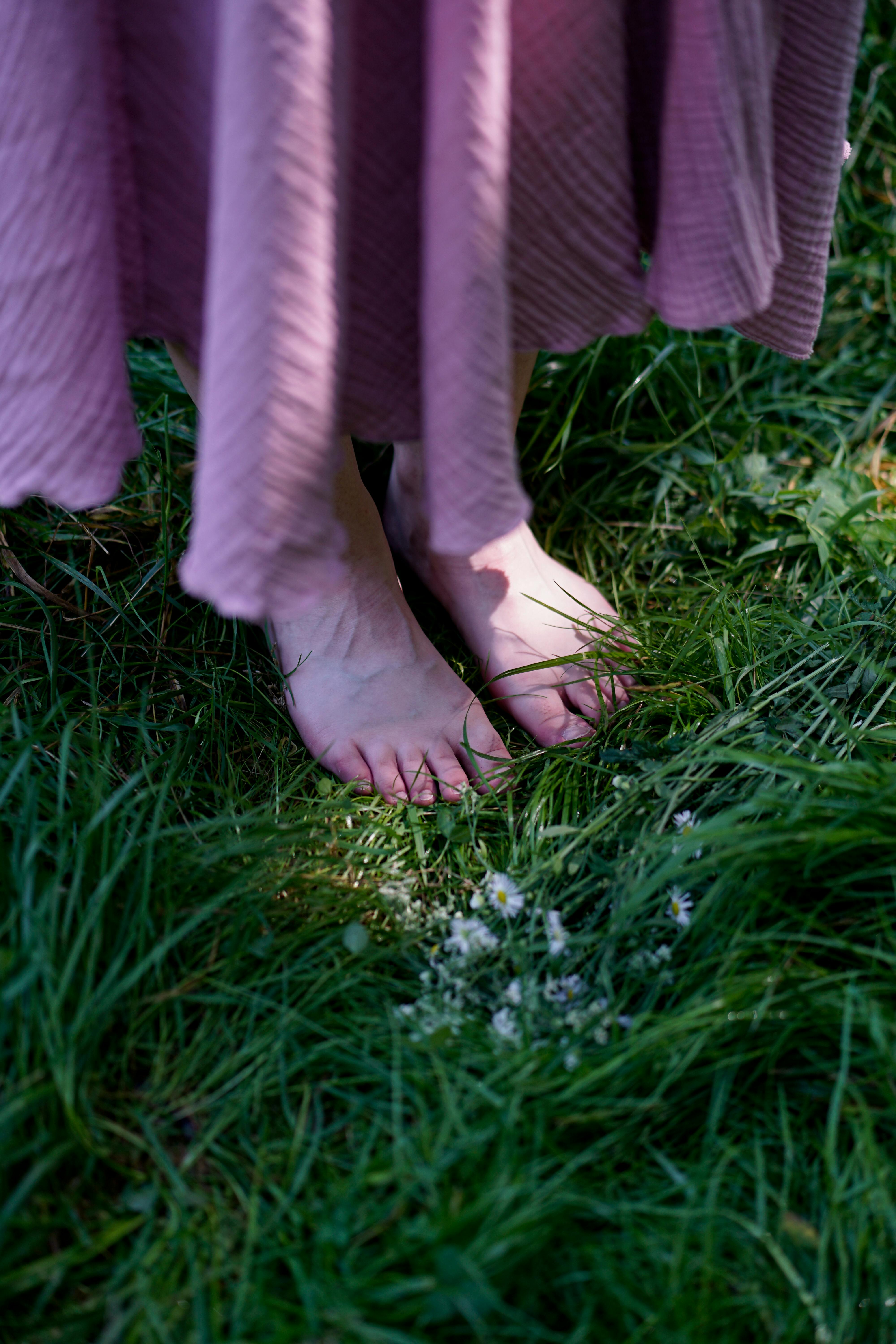 A barefoot woman stands on lush green grass with lilac skirt and flowers in Ternopil, Ukraine.