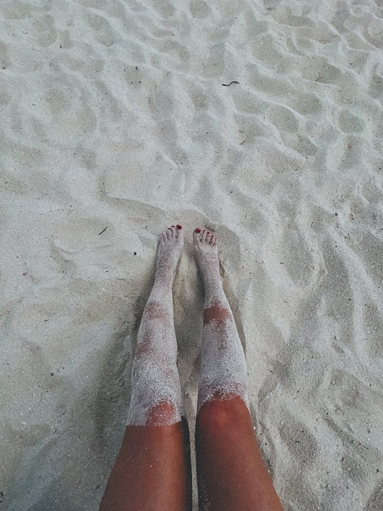 Sand On Legs Of Woman Sitting On Beach