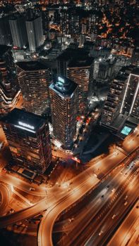 A dramatic aerial view of a bustling city at night with illuminated skyscrapers and highways.