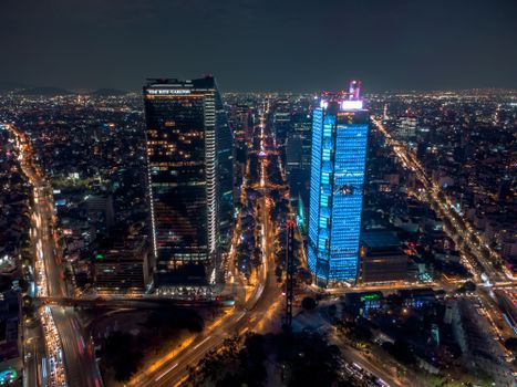 Stunning aerial view of illuminated skyscrapers in Mexico City at night, showcasing urban beauty.