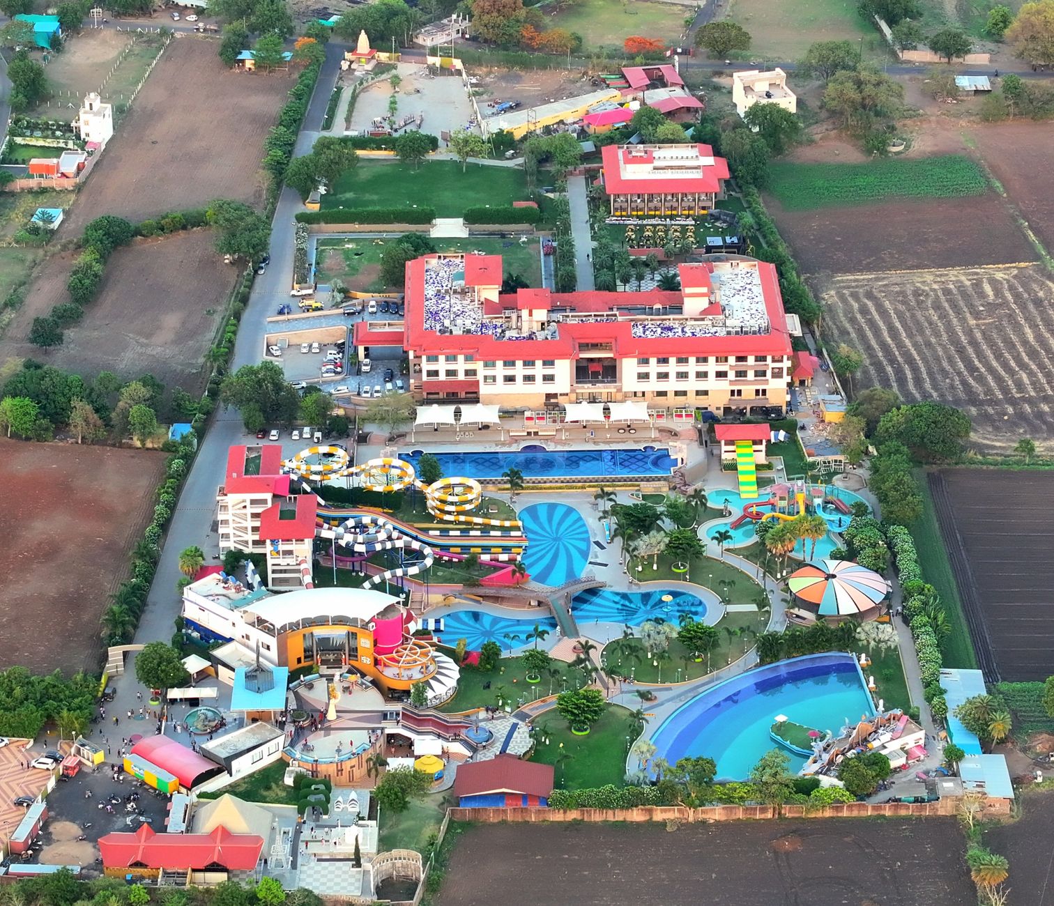 Aerial shot of a colorful waterpark surrounded by rural landscapes and fields.