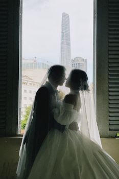 Newlyweds kissing in front of city skyline, capturing a romantic urban wedding moment.