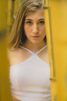 一位年轻女子的特写肖像，直视镜头，周围环绕着黄色树叶