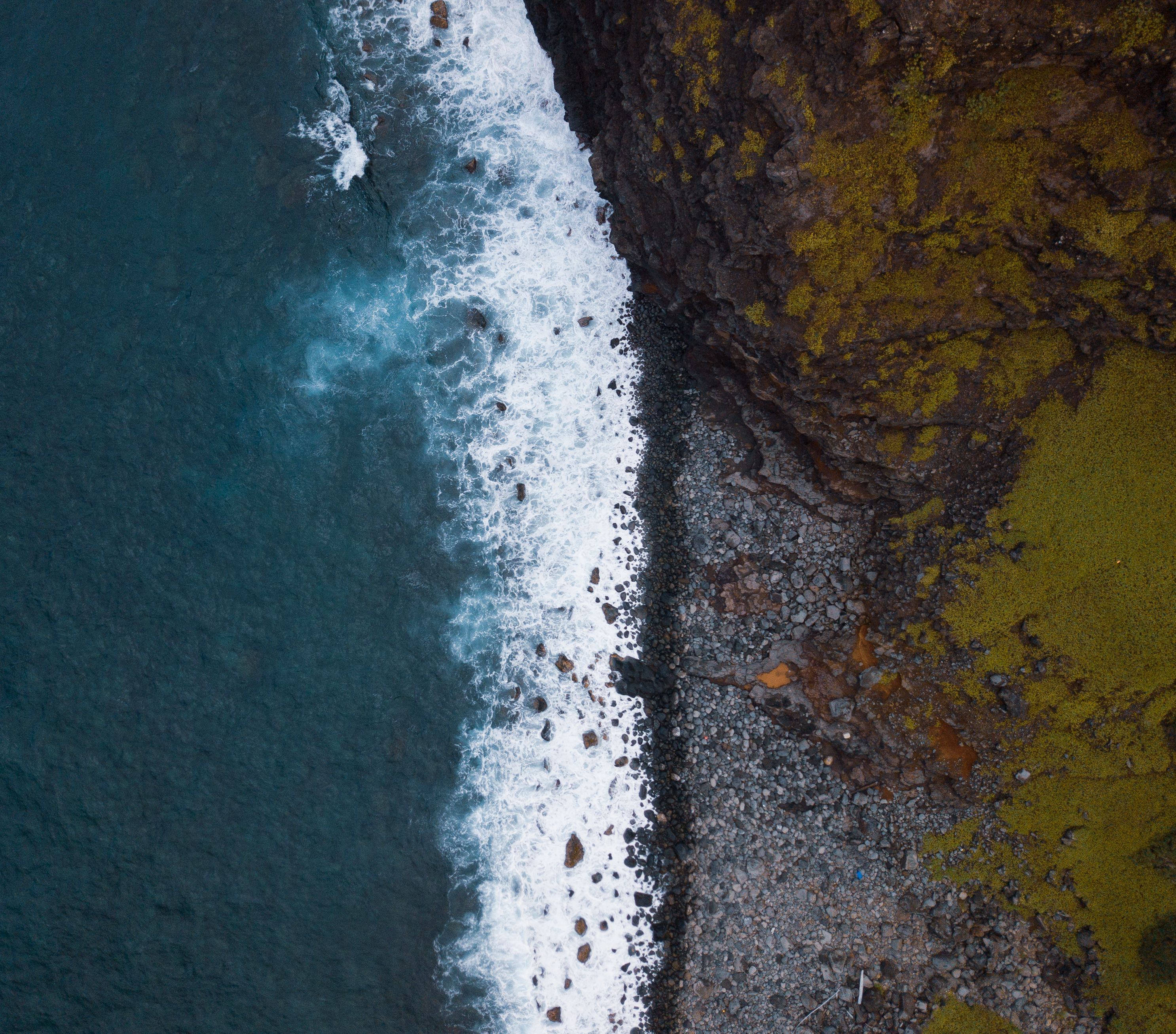 Dramatic aerial shot of the rocky coastline in Hana, Hawaii, showcasing waves crashing on the cliffs.