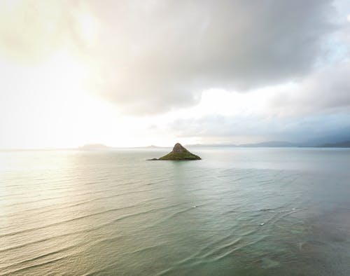 Overcast over Small Island on Sea Coast at Sunset