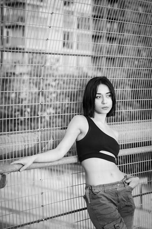 Woman in Top Standing by Fence in Black and White