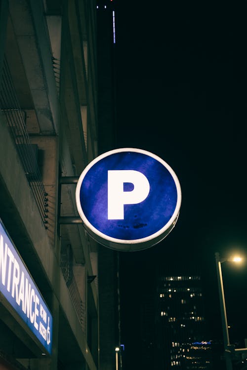Illuminated Parking Sign on Building on Night City Street