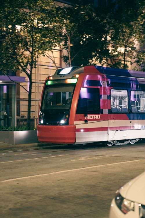 Free Vibrant red tramway traveling through an urban city street at night, showcasing urban public transport. Stock Photo