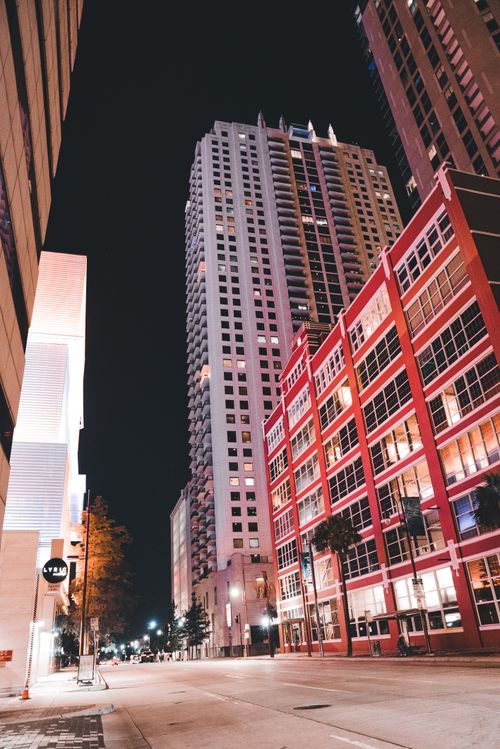 Free Nighttime cityscape featuring modern high-rise and lit streets in an urban setting. Stock Photo