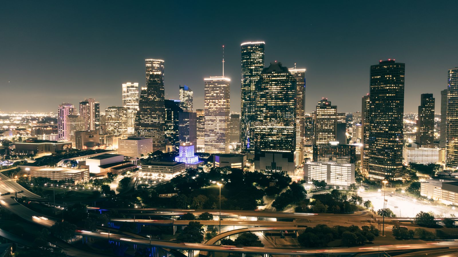 Stunning aerial view of Houston's illuminated skyline featuring skyscrapers and highways at night.