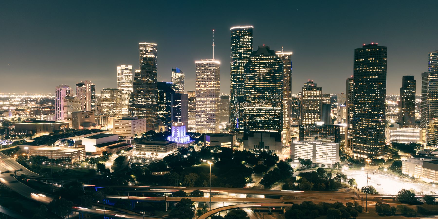 Stunning aerial view of Houston's illuminated skyline featuring skyscrapers and highways at night.