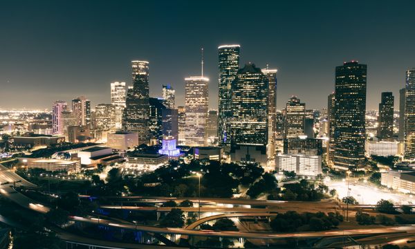 Stunning aerial view of Houston's illuminated skyline featuring skyscrapers and highways at night.