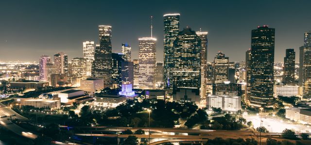 Stunning aerial view of Houston's illuminated skyline featuring skyscrapers and highways at night.