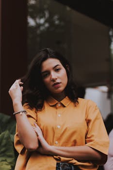 Stylish young woman posing outdoors in a casual shirt.