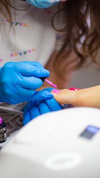 Detailed close-up of a pedicure session with blue gloves applying pink nail polish.