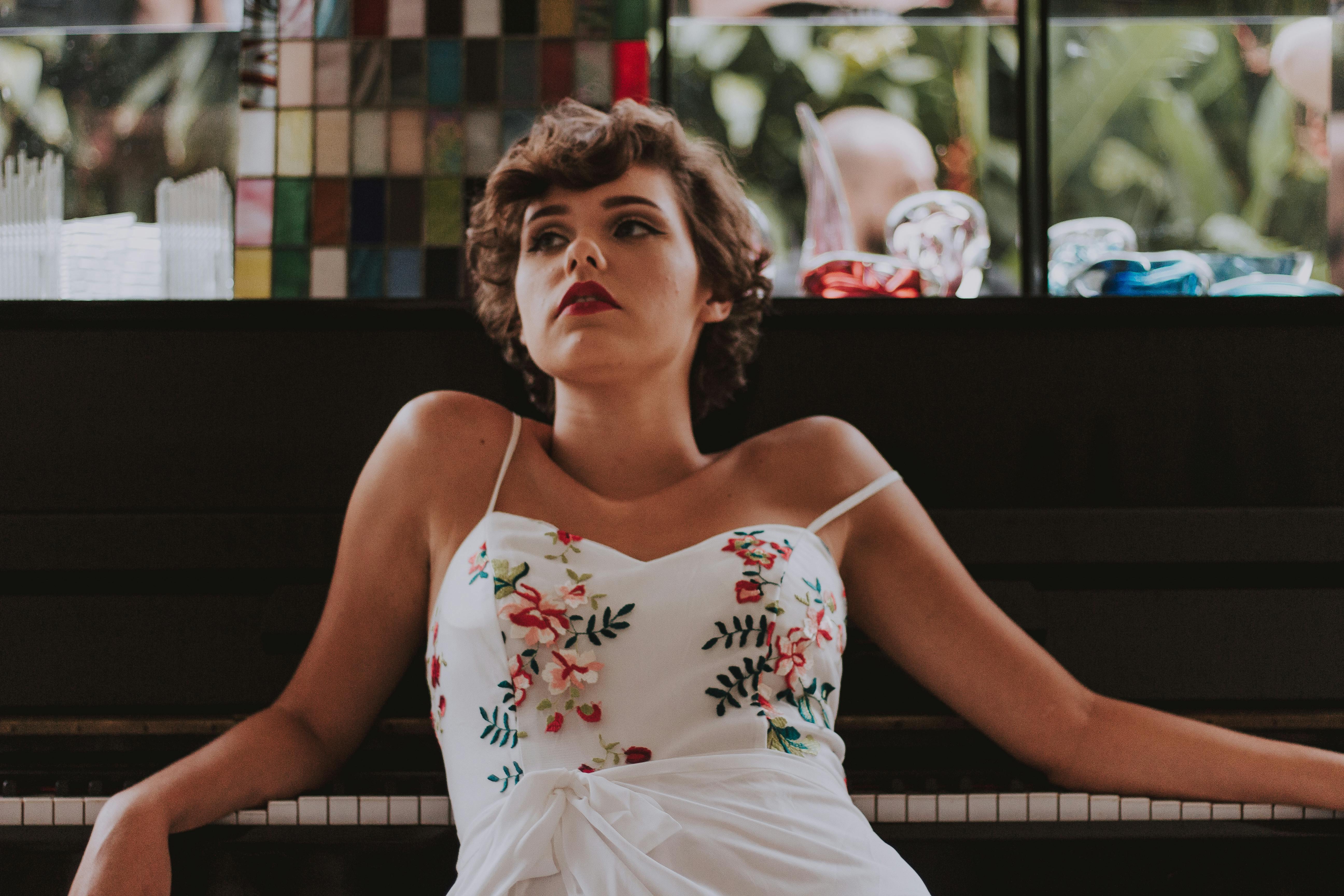 一位身着花卉连衣裙的优雅女子在钢琴前摆好姿势，魅力四溢