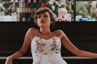 一位身着花卉连衣裙的优雅女子在钢琴前摆好姿势，魅力四溢