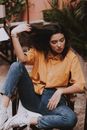 Woman Sitting on Wooden Chair While Holding Her Hair