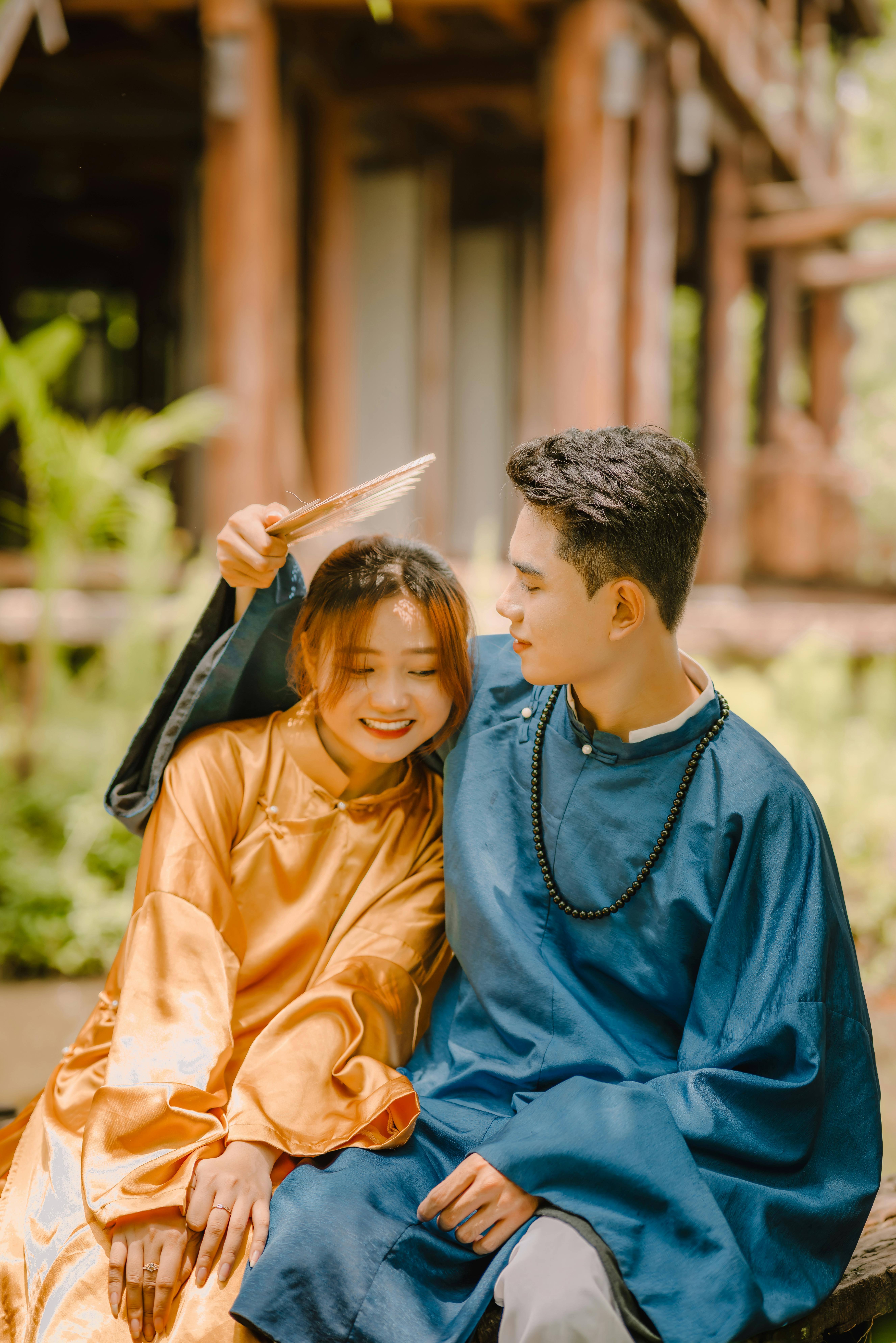 Free Young couple in traditional attire sitting outdoors, smiling and enjoying each other's company. Stock Photo