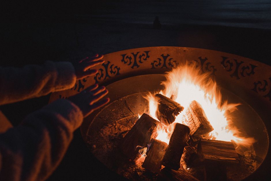 Hands warming by a crackling campfire on a cool night in Queenstown, New Zealand.