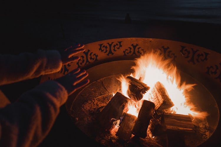 Warming Hands Over Bonfire At Night