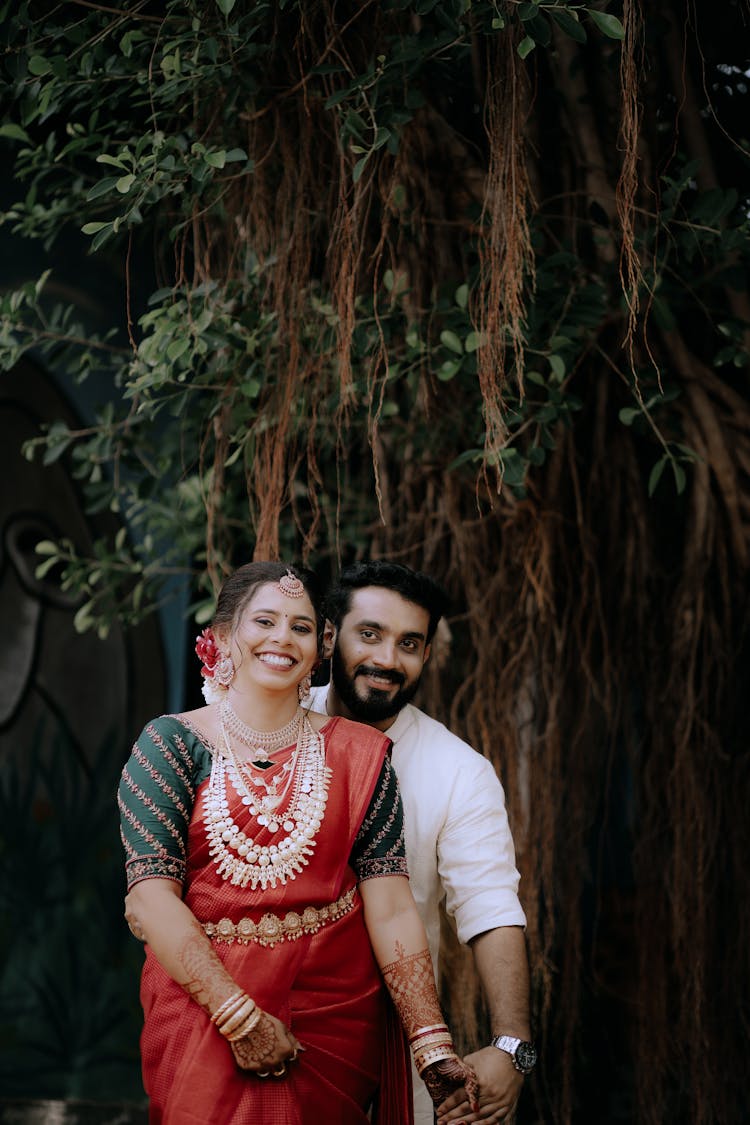 Smiling Indian Couple In Traditional Clothes Near Tree