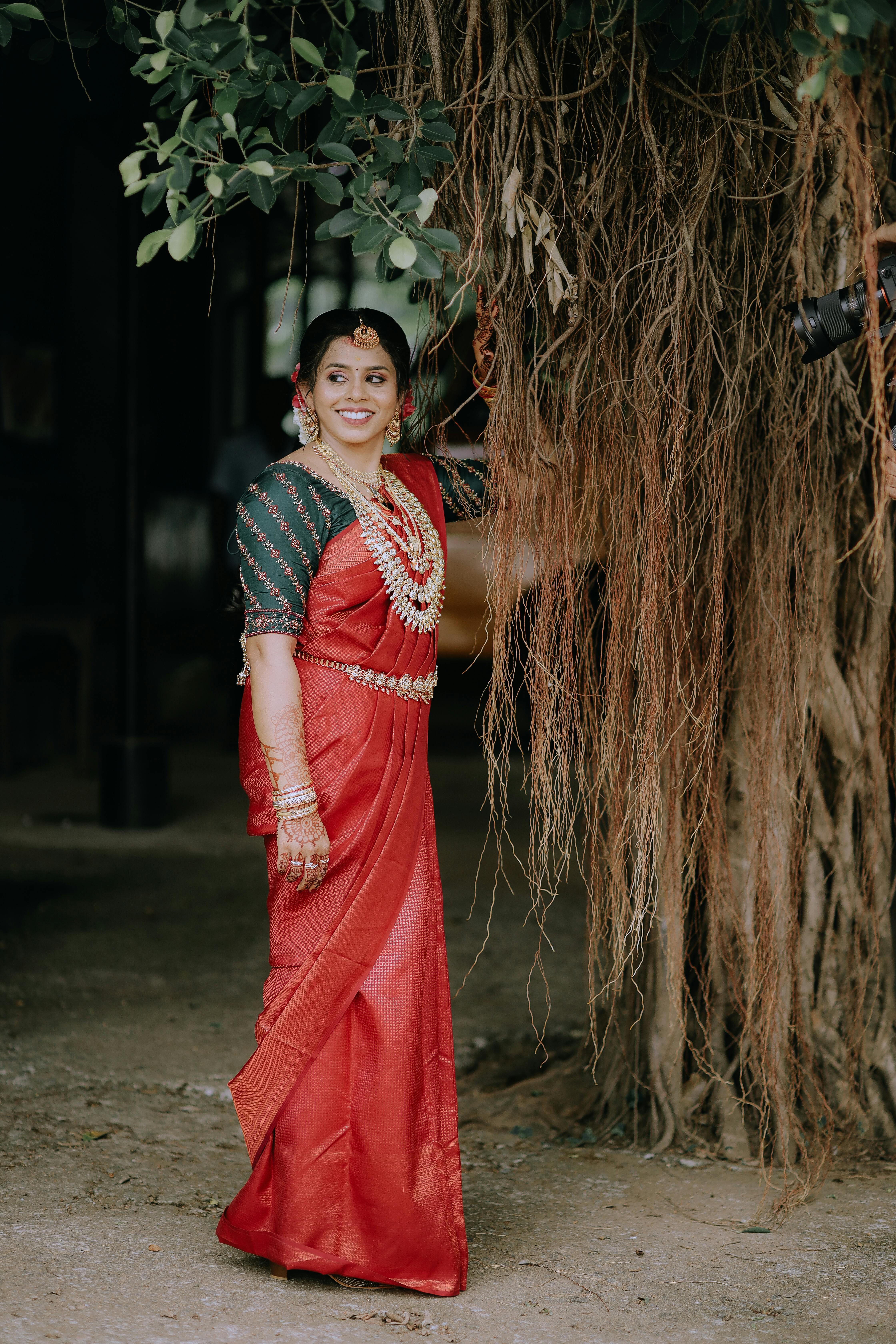 Photo of A south indian bride in a red saree poses for her bridal portrait.