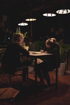 Two women engaged in conversation at a quaint café in Đà Lạt, Vietnam, surrounded by lush plants.