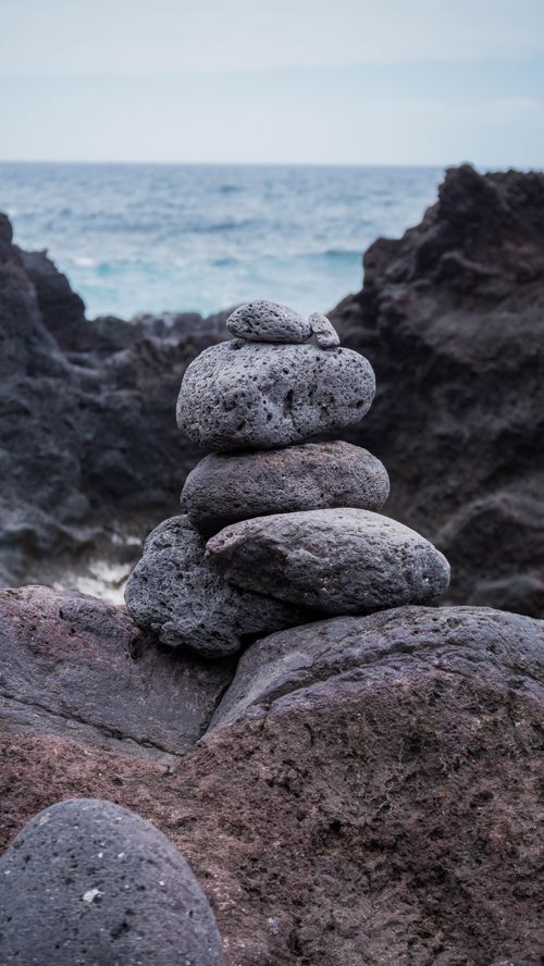 Free A serene stack of volcanic rocks on the shore, capturing nature's balance and beauty. Stock Photo