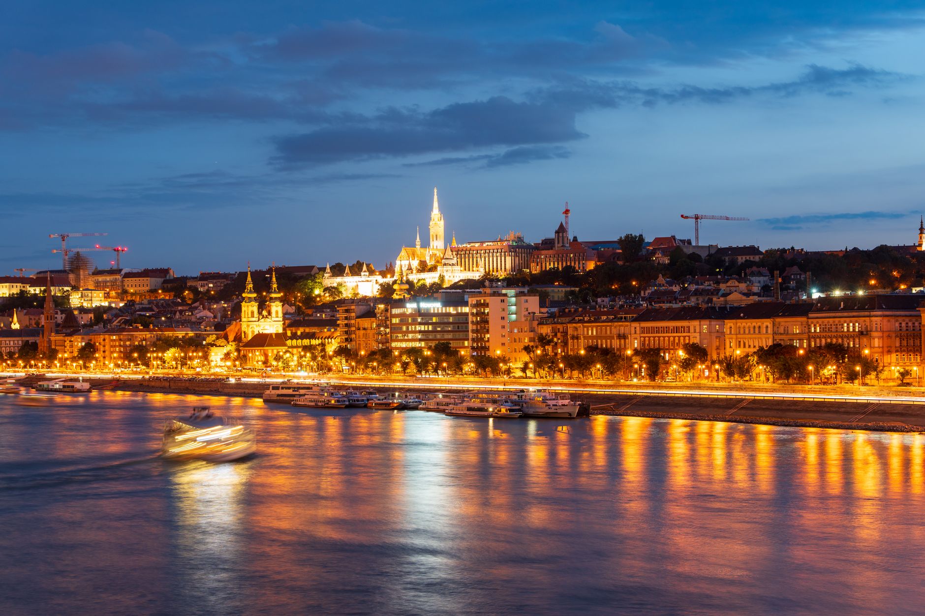 Capture of Budapest's cityscape with illuminated buildings along the Danube River at twilight.