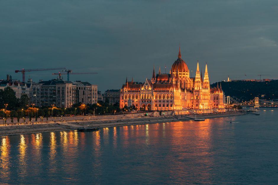 Stunning view of the illuminated Hungarian Parliament Building at dusk by the Danube River.
