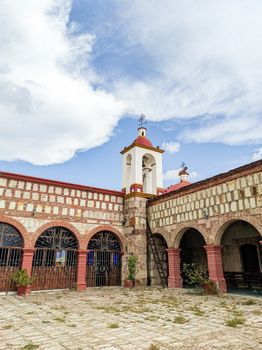 A beautiful courtyard in Tejas de Morelos, Oaxaca showcasing historic architecture and a tower under a bright sky.