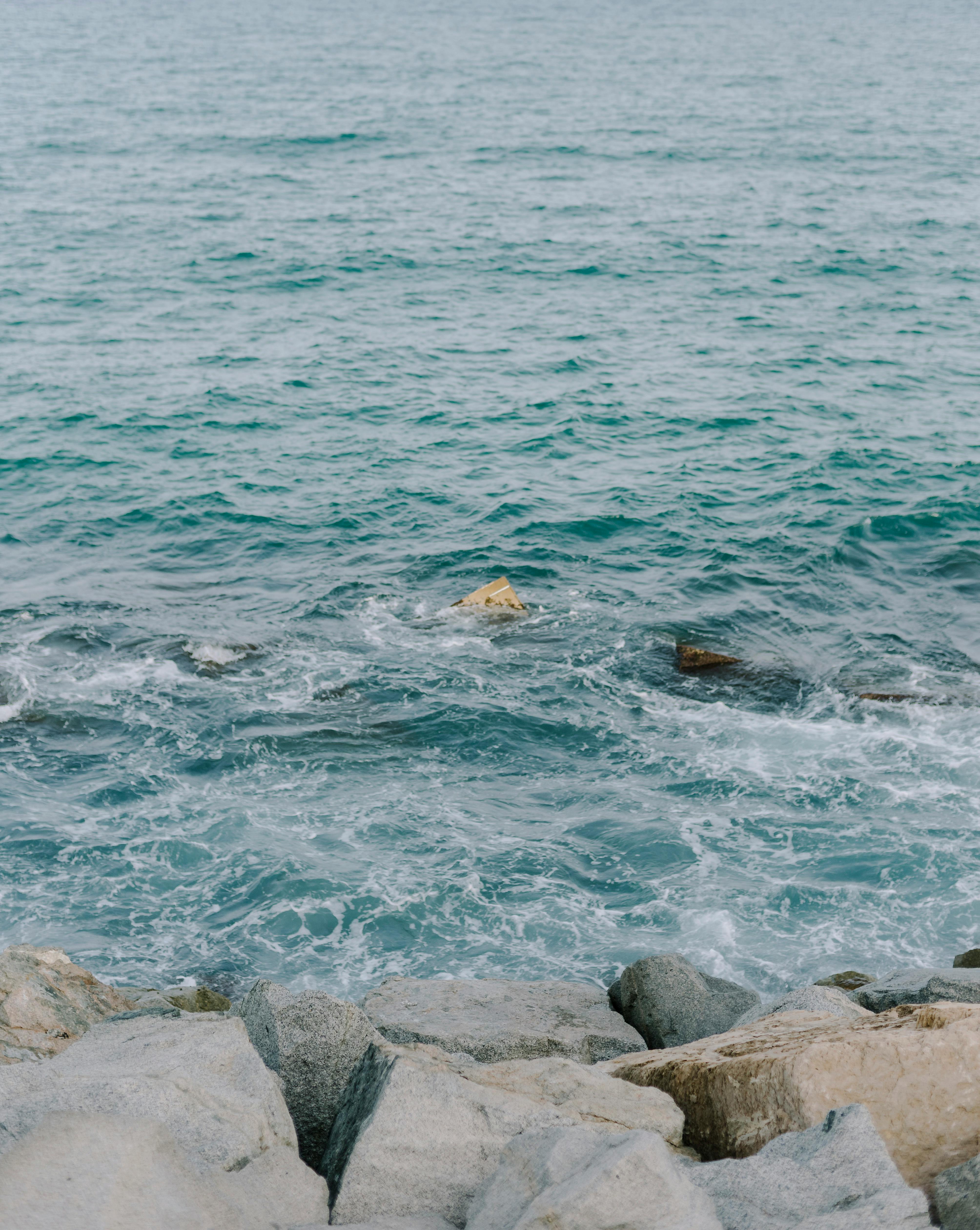 Calm ocean waves gently lapping against a rocky shoreline on a clear day, perfect for travel inspiration.