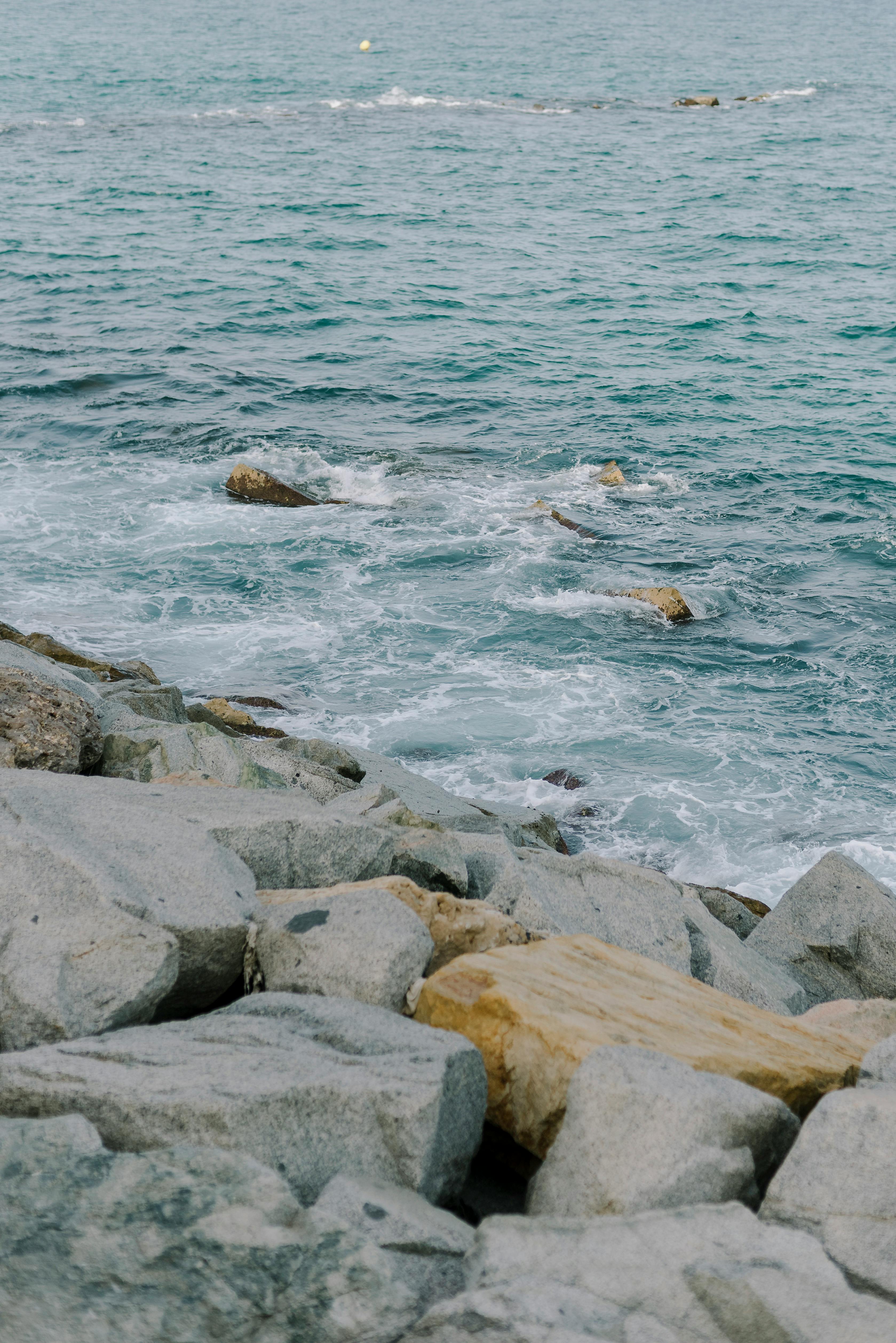 A scenic view of waves gently crashing on rocky shores under a clear sky.