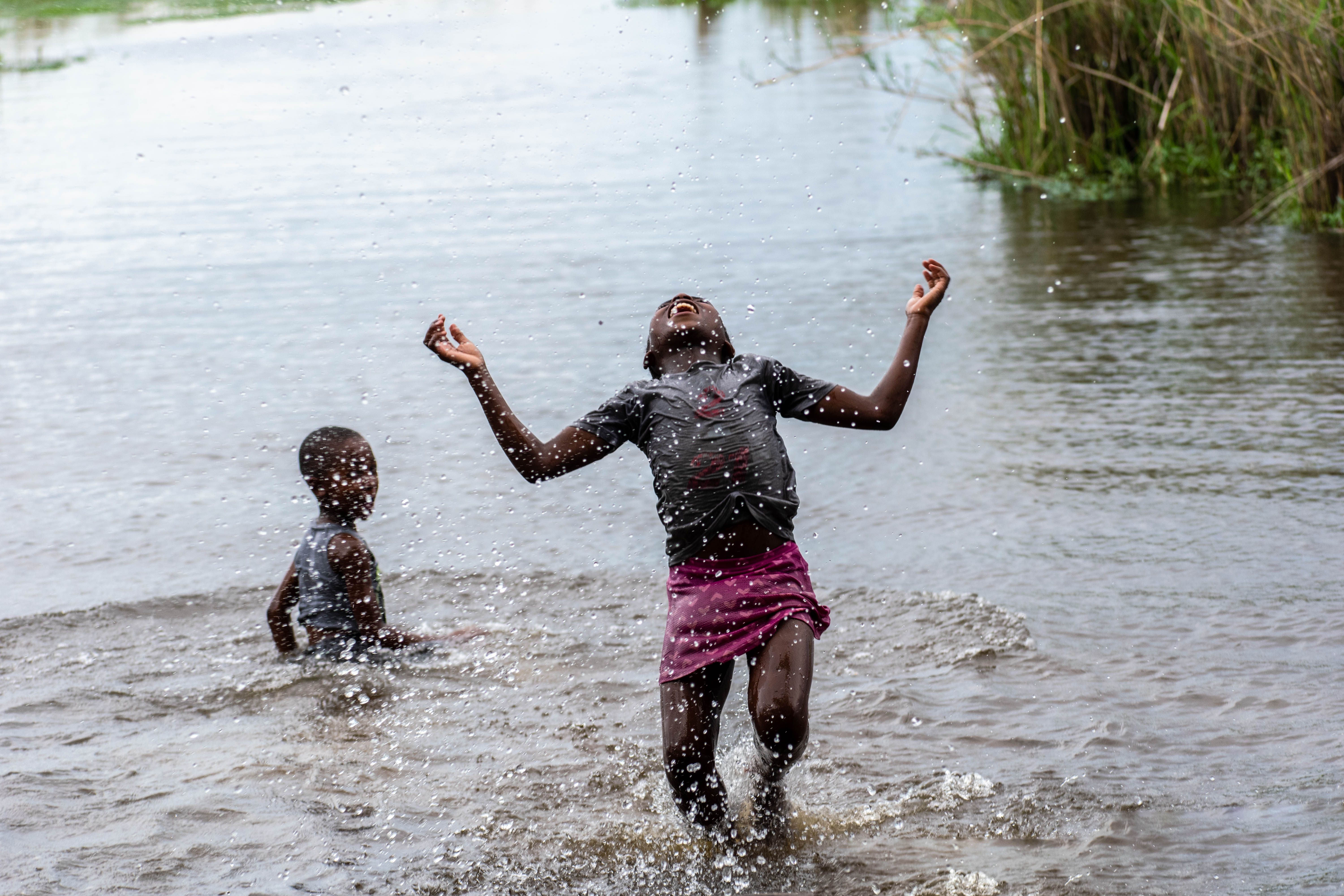 Two children joyfully splash and play in a river, embracing summertime fun and freedom.