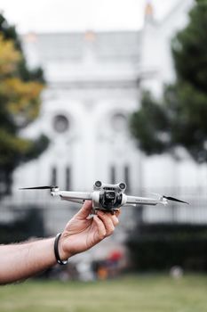 A person holding a drone ready for launch in front of a historic building.