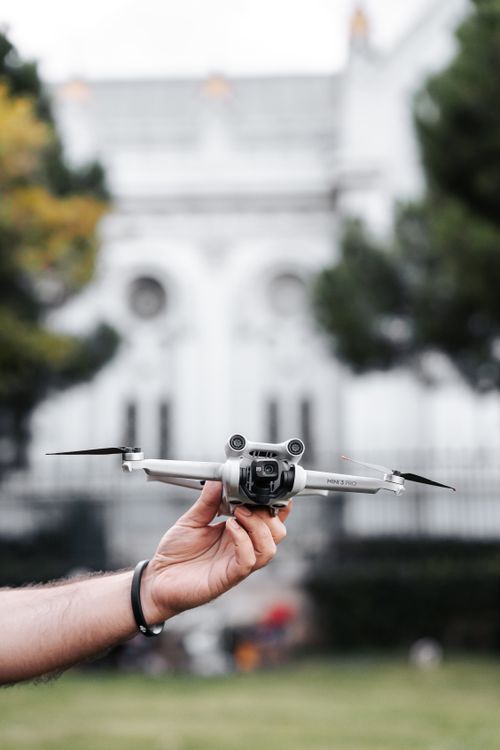 Free A person holding a drone ready for launch in front of a historic building. Stock Photo