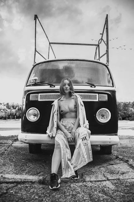 Stylish woman poses in front of a classic Volkswagen van. Black and white photography.